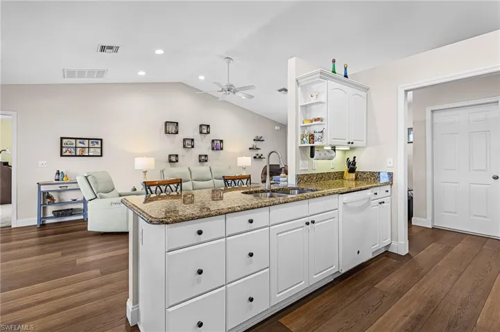 The lovely kitchen has granite countertops, white raised panel cabinets, white appliances, pantry closet off kitchen, and a breakfast nook with plantation shutters