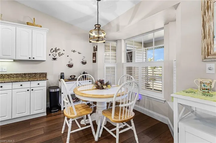 The lovely kitchen has granite countertops, white raised panel cabinets, white appliances, pantry closet off kitchen, and a breakfast nook with plantation shutters