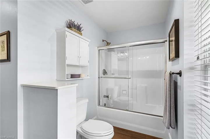 The large master suite has French doors to the lanai, lake view, carpet, a large walk-in closet, bright white quartz countertop with makeup setting area, classy fixtures with dual mirrors, shower tub combination, and linen closet for extra storage
