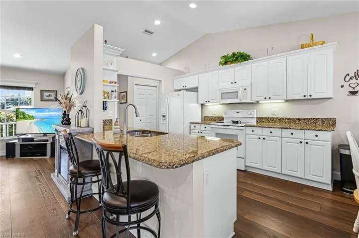 The lovely kitchen has granite countertops, white raised panel cabinets, white appliances, pantry closet off kitchen, and a breakfast