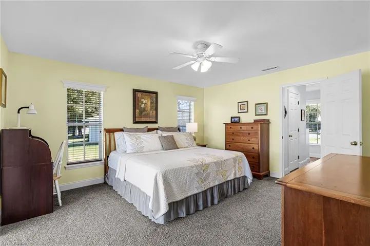 The large master suite has French doors to the lanai, lake view, carpet, a large walk-in closet, bright white quartz countertop with makeup setting area, classy fixtures with dual mirrors, shower tub combination, and linen closet for extra storage