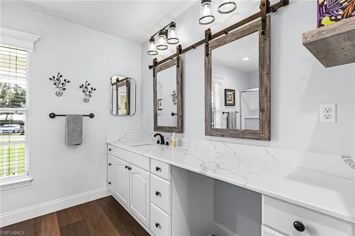 The large master suite has French doors to the lanai, lake view, carpet, a large walk-in closet, bright white quartz countertop with makeup setting area, classy fixtures with dual mirrors, shower tub combination, and linen closet for extra storage