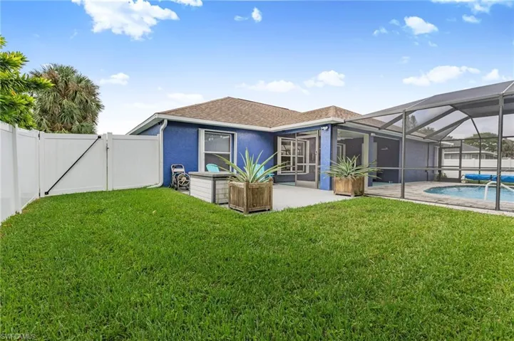 Back of property with a sunroom, a lanai, a gate, a shingled roof, and a patio area