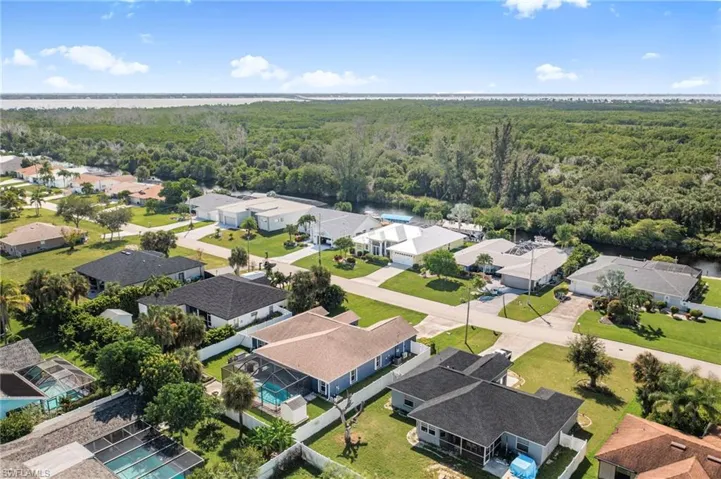 Aerial perspective of suburban area featuring a forest and a nearby body of water