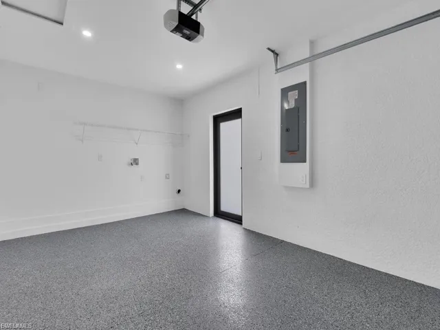 Garage featuring electric panel, a garage door opener, and recessed lighting