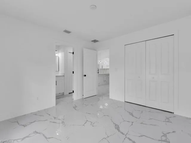Unfurnished bedroom with a closet and light marble finish floors