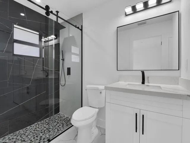 Full bathroom with vanity, a stall shower, and light marble finish flooring