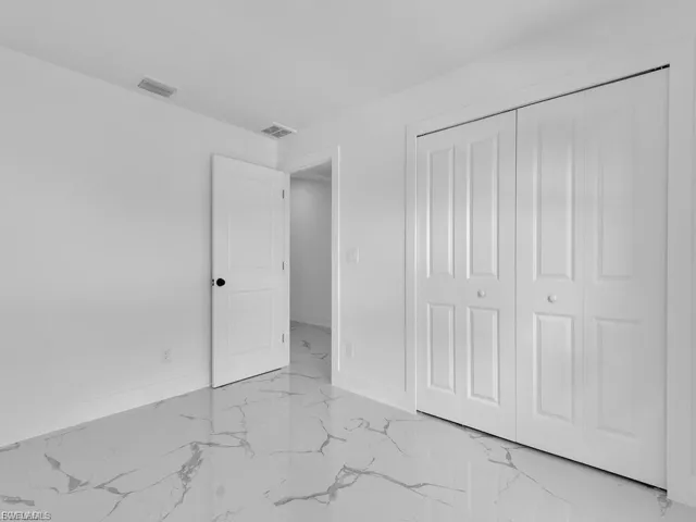 Unfurnished bedroom featuring a closet and light marble finish flooring