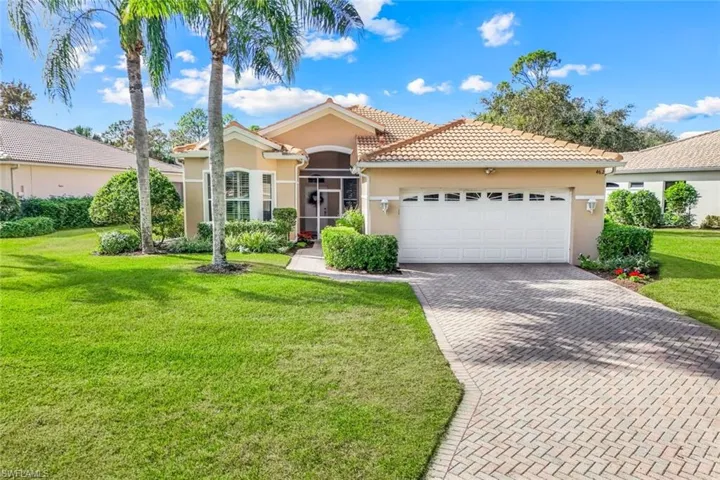 View of front of home with stucco siding, decorative driveway, a tiled roof, a sunroom, and a front lawn