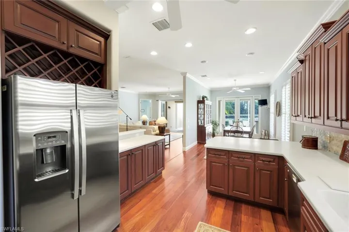 Kitchen with stainless steel appliances, a peninsula, dark wood-type flooring, ornamental molding, and decorative backsplash