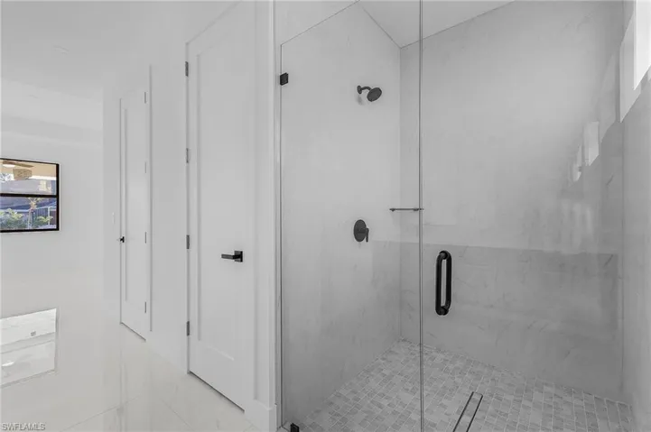 Full bathroom featuring a marble finish shower, tile patterned floors, and plenty of natural light