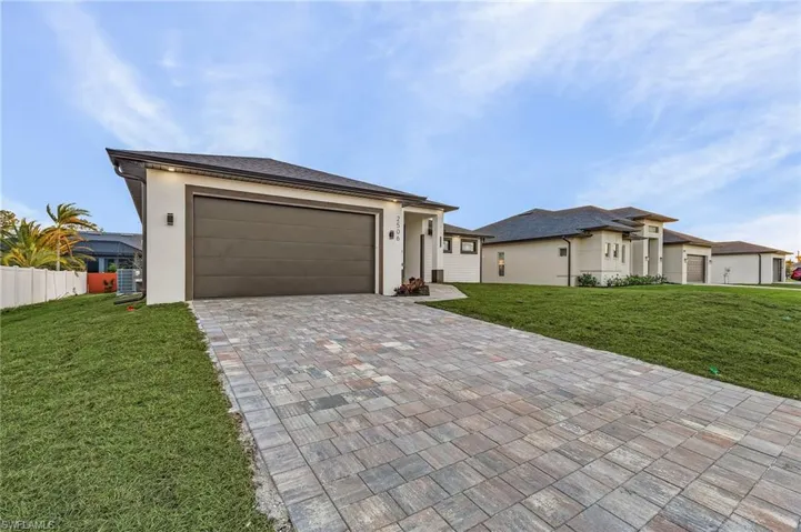 Prairie-style home featuring decorative driveway, stucco siding, and an attached garage