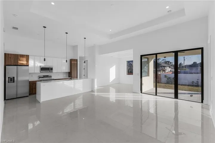 Unfurnished living room with a raised ceiling, a high ceiling, and recessed lighting