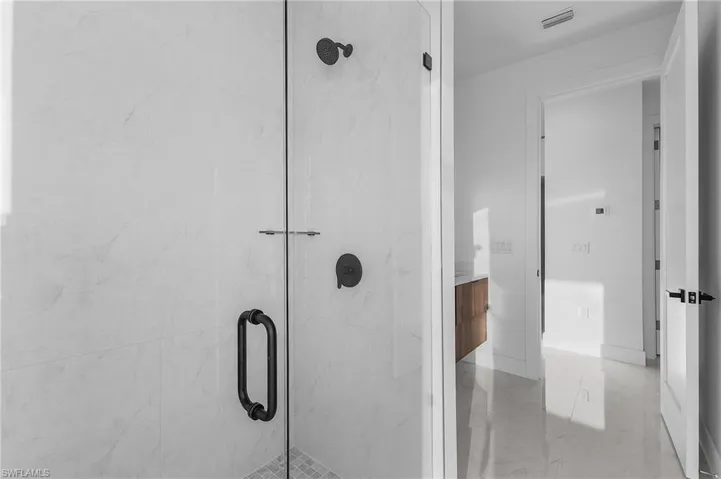 Bathroom with vanity and a marble finish shower