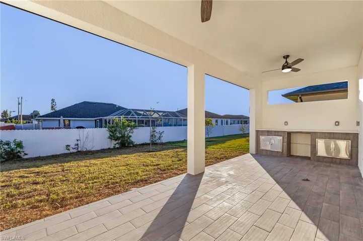 Fenced backyard with area for grilling, a ceiling fan, a patio, and a residential view