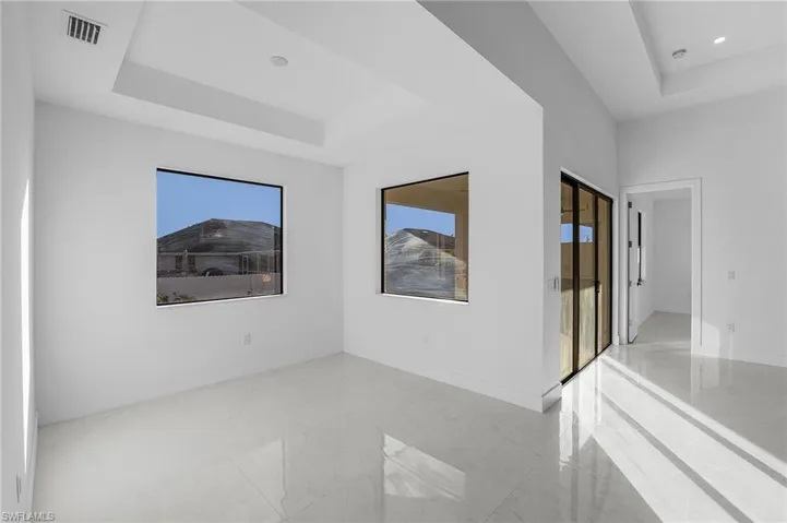 Empty room featuring a raised ceiling and light marble finish flooring