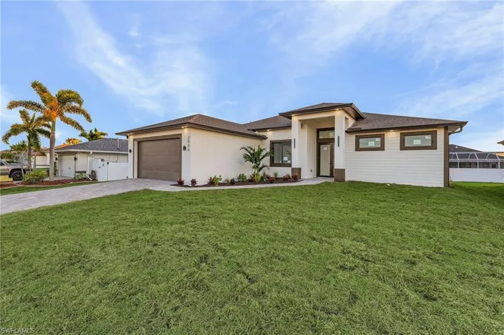 Prairie-style home with a front yard, driveway, a garage, and stucco siding