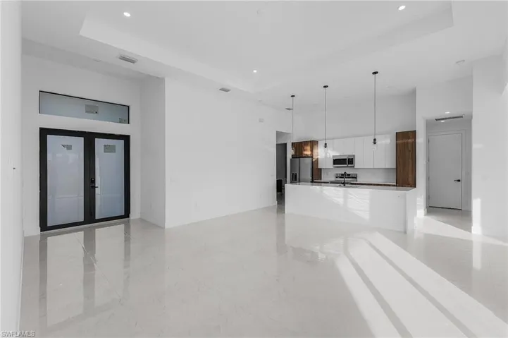 Unfurnished living room featuring a raised ceiling, recessed lighting, french doors, and a towering ceiling