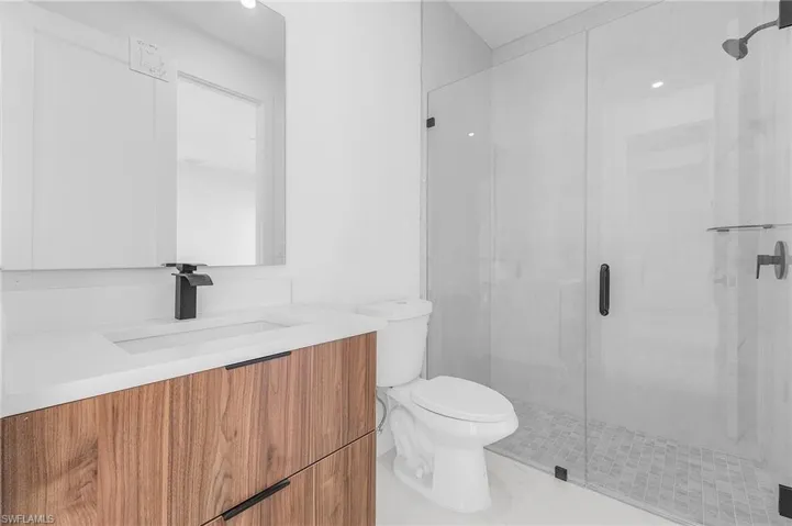 Full bath with vanity, a marble finish shower, and light tile patterned flooring