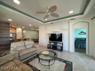 Living room featuring a raised ceiling, a ceiling fan, and recessed lighting