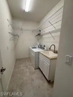 Washroom with baseboards, a sink, cabinet space, and independent washer and dryer