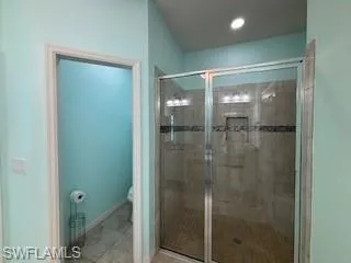 Full bathroom with baseboards, a shower stall, and toilet
