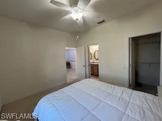 Bedroom with a walk in closet, visible vents, baseboards, a closet, and connected bathroom