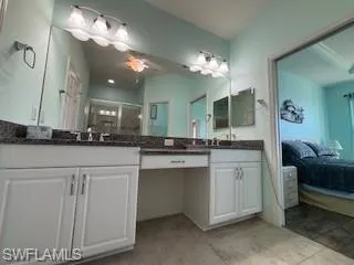 Ensuite bathroom with double vanity, a shower with shower door, a sink, and connected bathroom