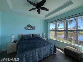 Bedroom featuring ornamental molding, wood finished floors, and a raised ceiling