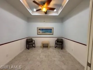 Unfurnished room with a raised ceiling, ornamental molding, and ceiling fan