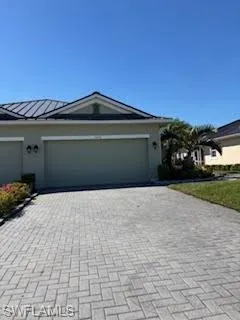 Single story home featuring an attached garage, stucco siding, decorative driveway, a standing seam roof, and metal roof