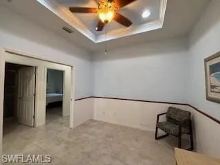 Unfurnished bedroom with crown molding, visible vents, and a raised ceiling