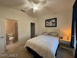 Bedroom with visible vents, carpet floors, baseboards, ceiling fan, and ensuite bath