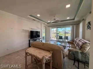 Living area with a raised ceiling, tile patterned floors, a ceiling fan, and recessed lighting