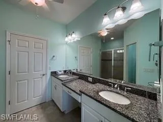 Bathroom with double vanity, a sink, ceiling fan, and a stall shower
