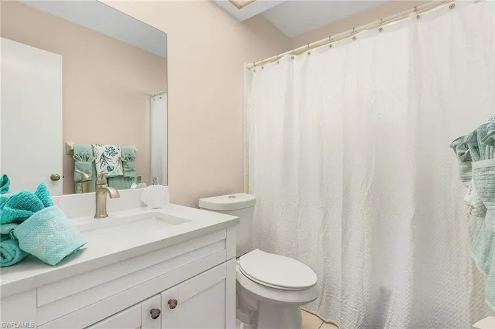 Bathroom with walk in shower, tile patterned flooring, vanity, and toilet