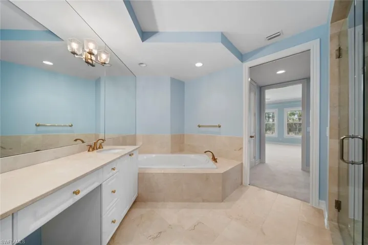Bathroom featuring vanity, plus walk in shower, and a chandelier