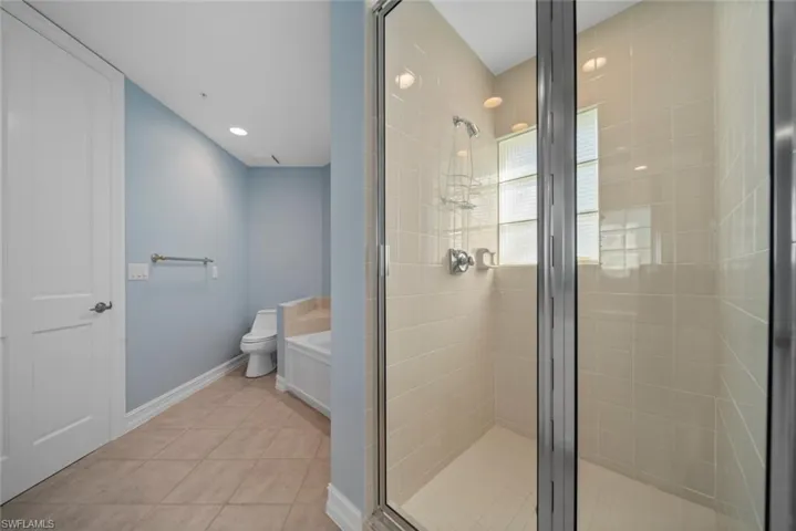 Bathroom with toilet, independent shower and bath, and tile patterned floors