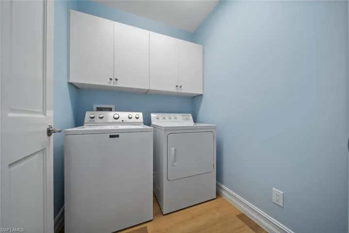 Clothes washing area featuring cabinets, separate washer and dryer, and light hardwood / wood-style flooring