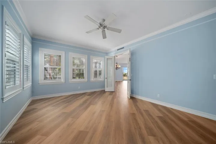 Unfurnished room featuring ceiling fan with notable chandelier, hardwood / wood-style flooring, and crown molding