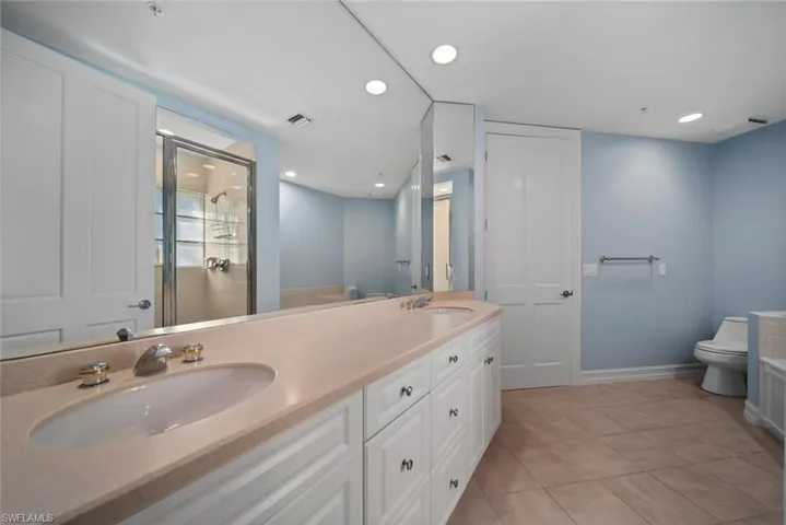 Bathroom featuring toilet, an enclosed shower, vanity, and tile patterned floors
