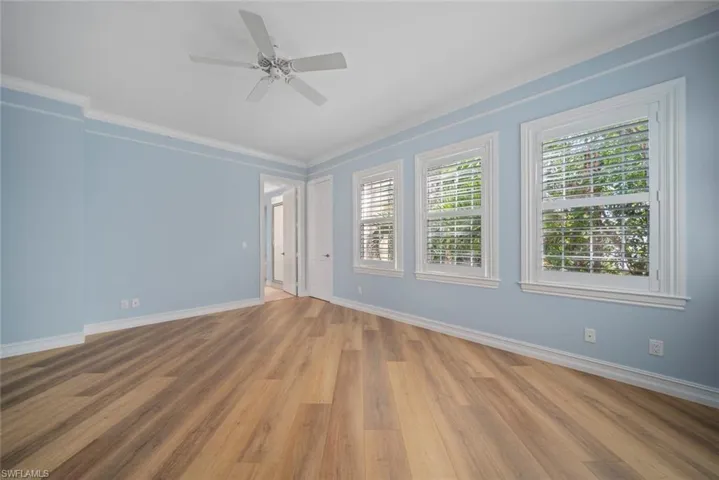 Empty room featuring ceiling fan, light wood-type flooring, and crown molding