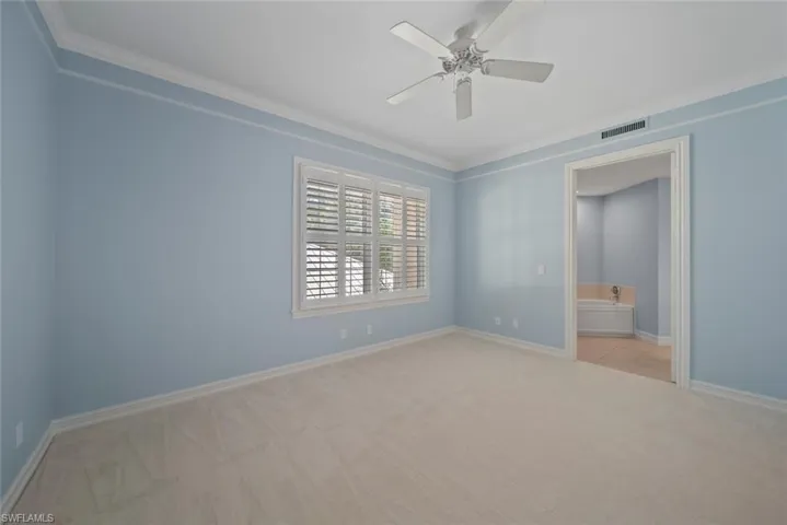 Carpeted spare room with ceiling fan and ornamental molding