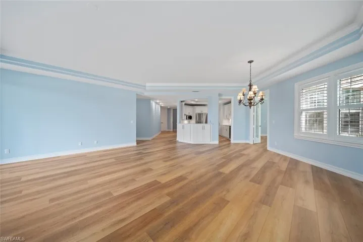 Unfurnished living room with ornamental molding, light hardwood / wood-style flooring, and a notable chandelier