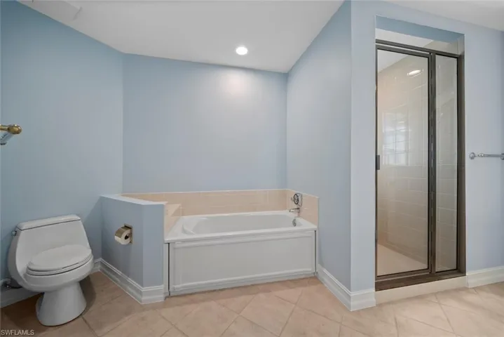 Bathroom featuring tile patterned floors, toilet, and separate shower and tub