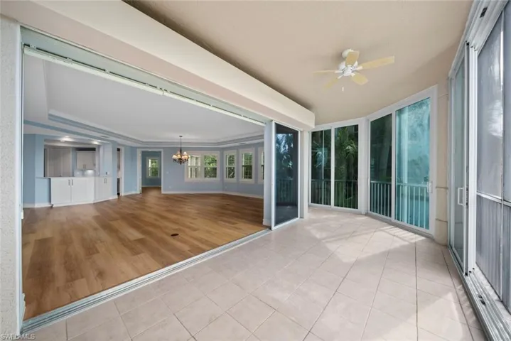 Unfurnished sunroom featuring ceiling fan with notable chandelier