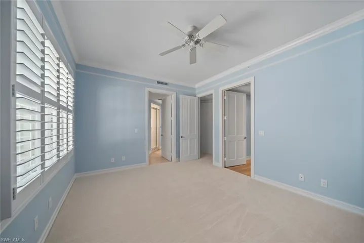 Empty room featuring ornamental molding, light carpet, and ceiling fan