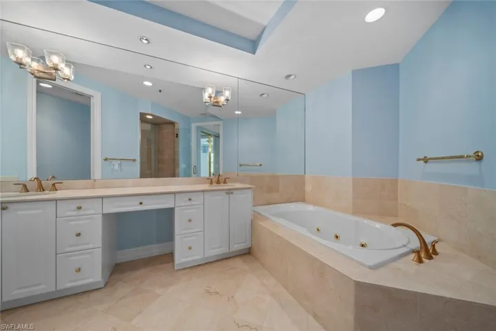 Bathroom featuring vanity, a notable chandelier, and tiled tub
