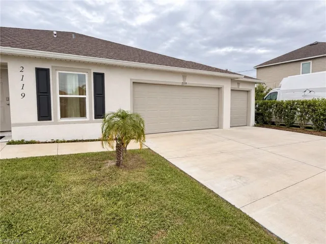 Stucco exterior featuring black shutters, a concrete driveway, and a three-car garage