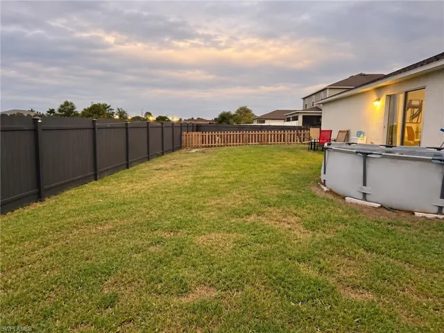 Backyard featuring a grass lawn, privacy fencing, and wood-picket fencing